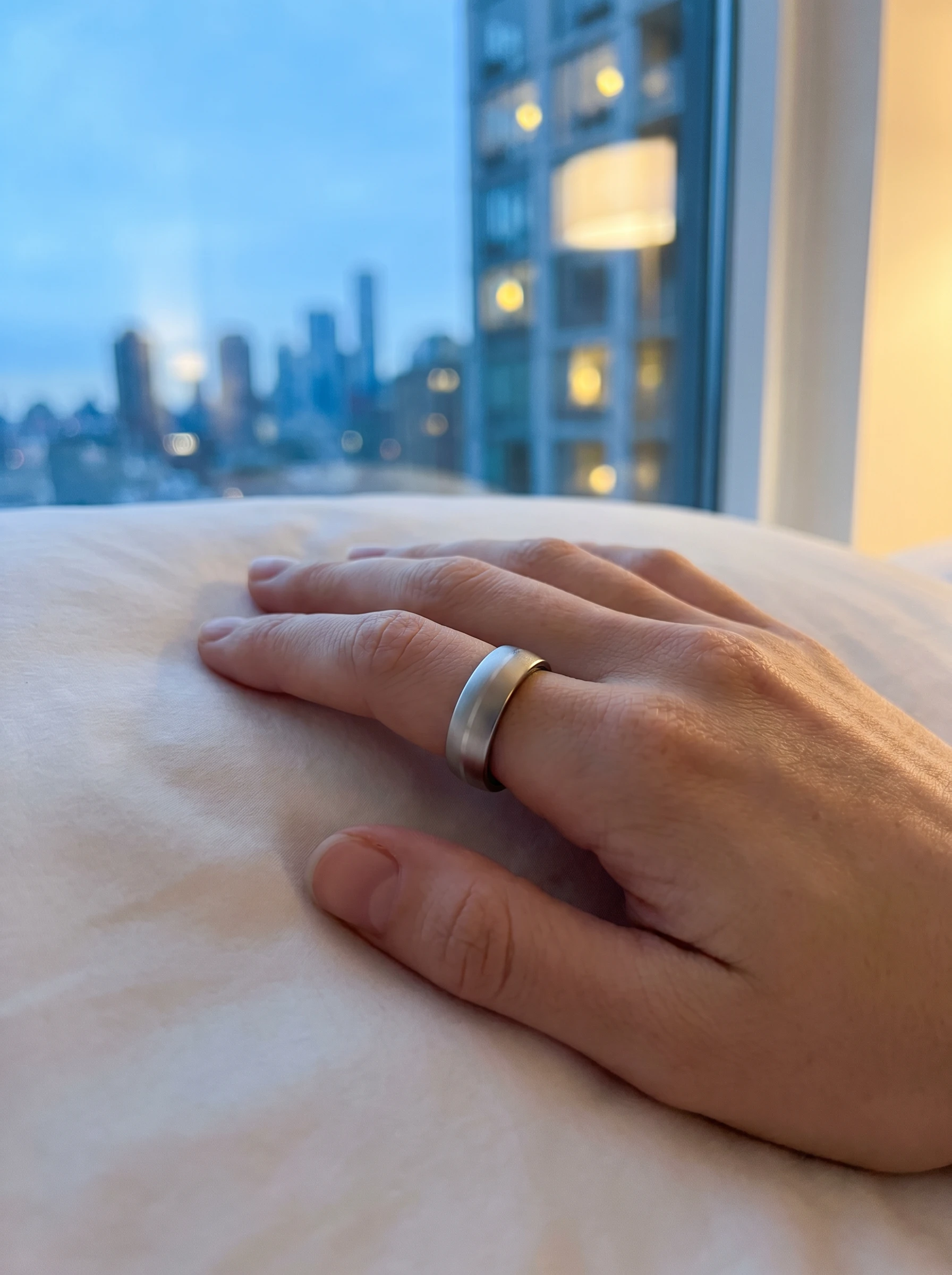 Hand mit N2 Pro Ring auf dem Bett, Skyline im Morgenlicht